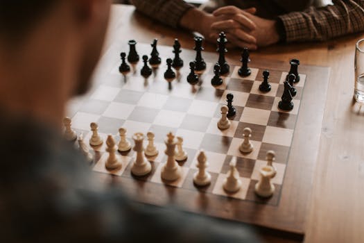 Chess players engaged in a strategic game on a wooden table, showcasing thought and strategy.