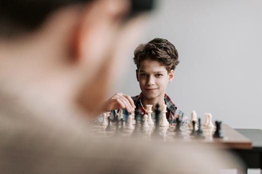 A young boy plays chess indoors, focusing intently on the chessboard.